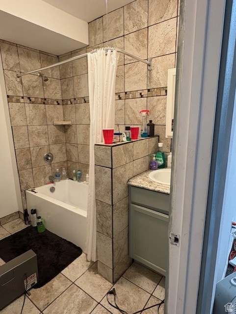 Full bath featuring tile patterned flooring, shower / bath combo with shower curtain, vanity, and tile walls