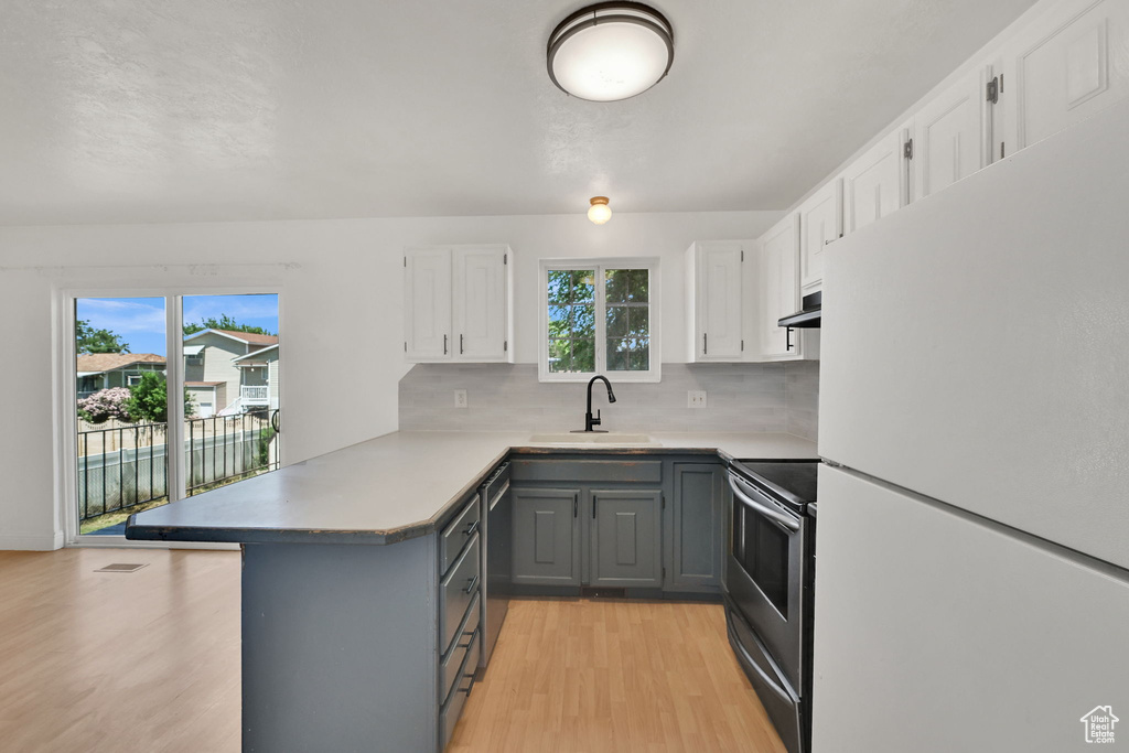Kitchen with appliances with stainless steel finishes, gray cabinets, a peninsula, and white cabinetry