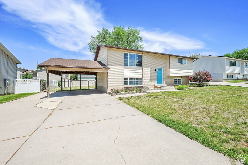 Split foyer home with an attached carport, driveway, and brick siding