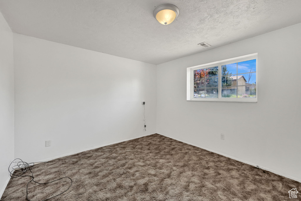 Unfurnished room with carpet, baseboards, and a textured ceiling