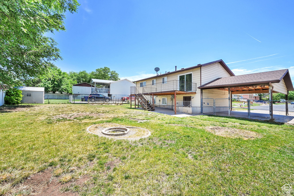 Rear view of house featuring a fire pit, stairs, and a carport