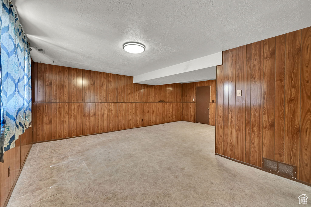 Carpeted spare room with a textured ceiling and wooden walls
