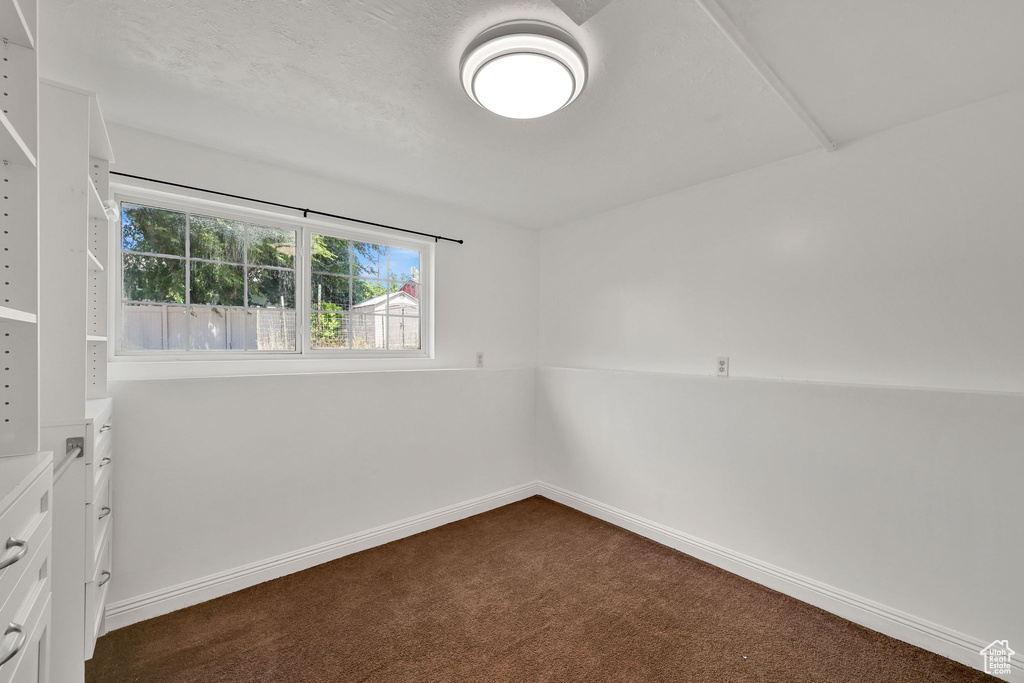 Empty room with dark carpet and baseboards