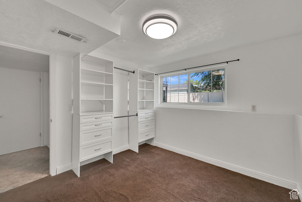 Unfurnished bedroom featuring dark carpet, a textured ceiling, and baseboards