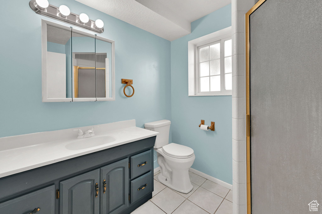 Full bathroom with tile patterned flooring, vanity, toilet, a shower stall, and baseboards