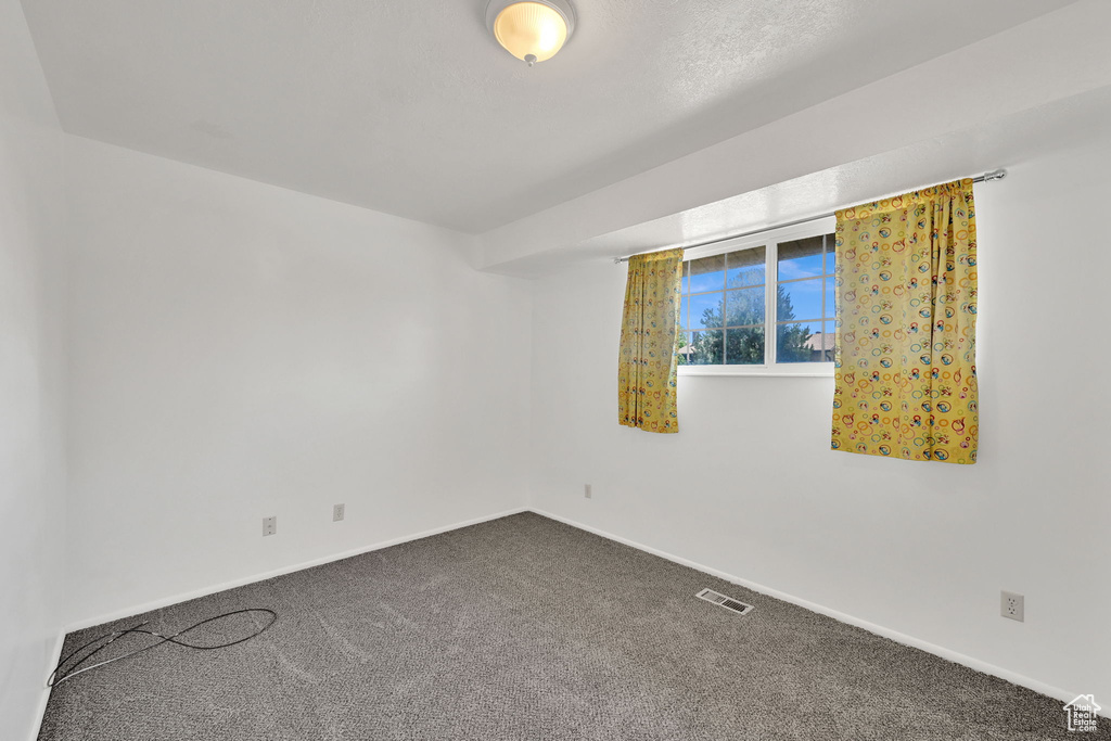 Unfurnished room featuring dark colored carpet and baseboards