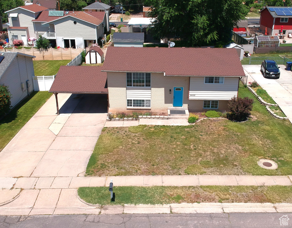 View of front facade with driveway, a shingled roof, a residential view, brick siding, and a carport