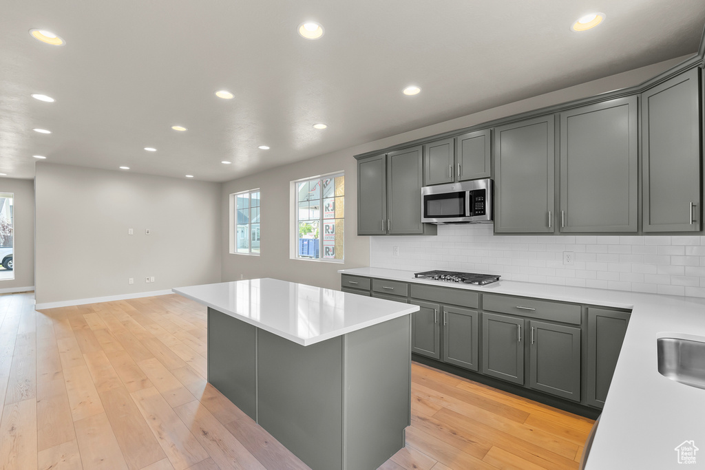 Kitchen featuring stainless steel appliances, light countertops, tasteful backsplash, recessed lighting, and a center island