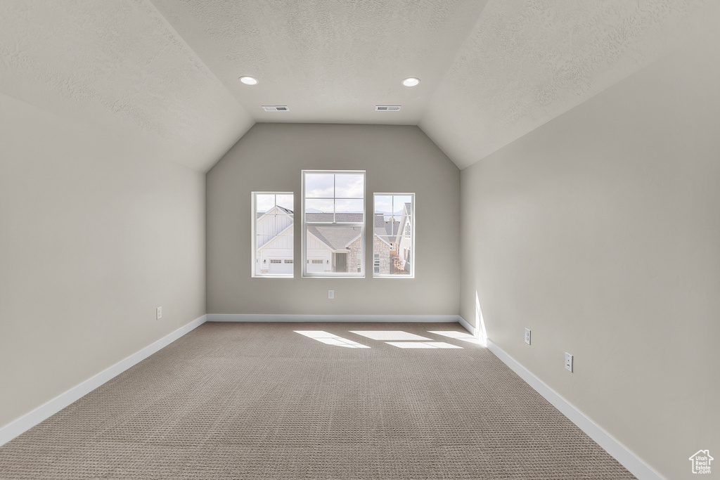 Additional living space with a textured ceiling, carpet flooring, lofted ceiling, baseboards, and recessed lighting