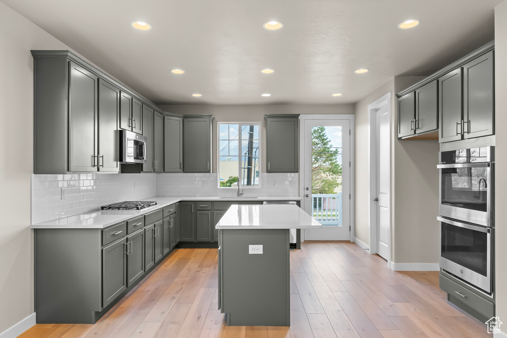 Kitchen featuring appliances with stainless steel finishes, baseboards, tasteful backsplash, a sink, and recessed lighting