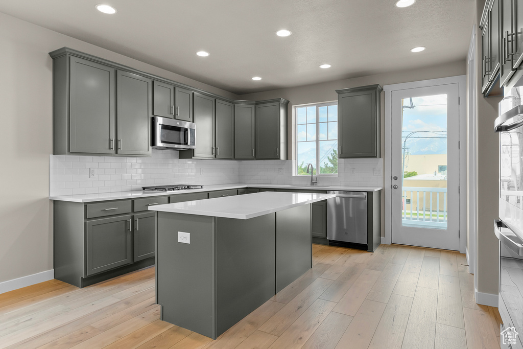 Kitchen featuring stainless steel appliances, baseboards, a center island, light countertops, and recessed lighting