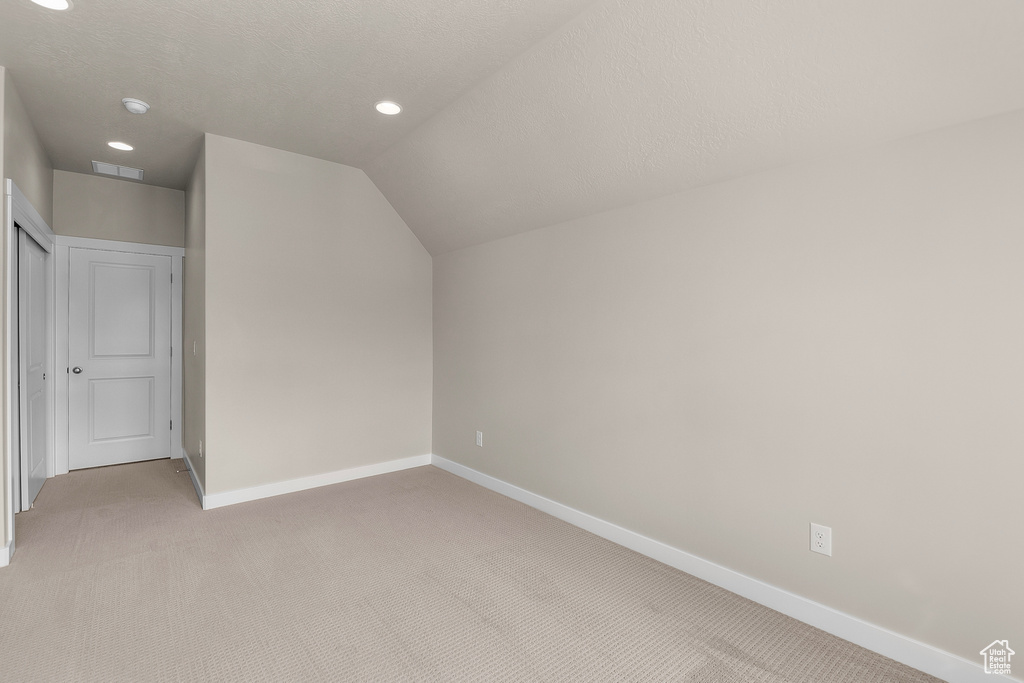 Additional living space featuring light colored carpet, baseboards, lofted ceiling, and recessed lighting