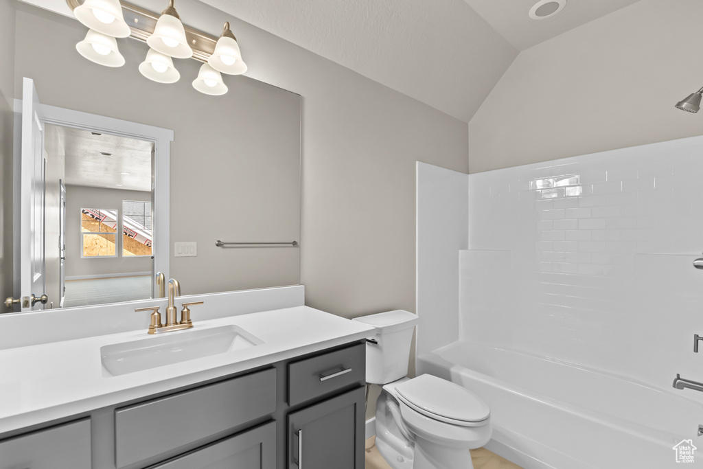 Full bathroom featuring vanity, toilet, tub / shower combination, and vaulted ceiling