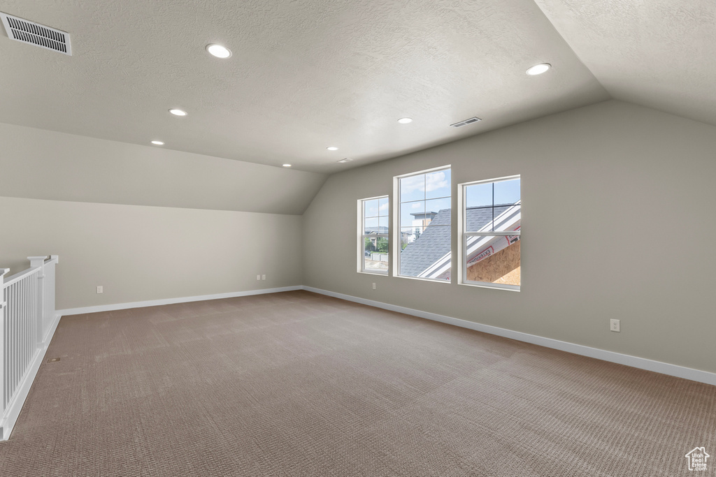 Additional living space with lofted ceiling, baseboards, light colored carpet, a textured ceiling, and recessed lighting