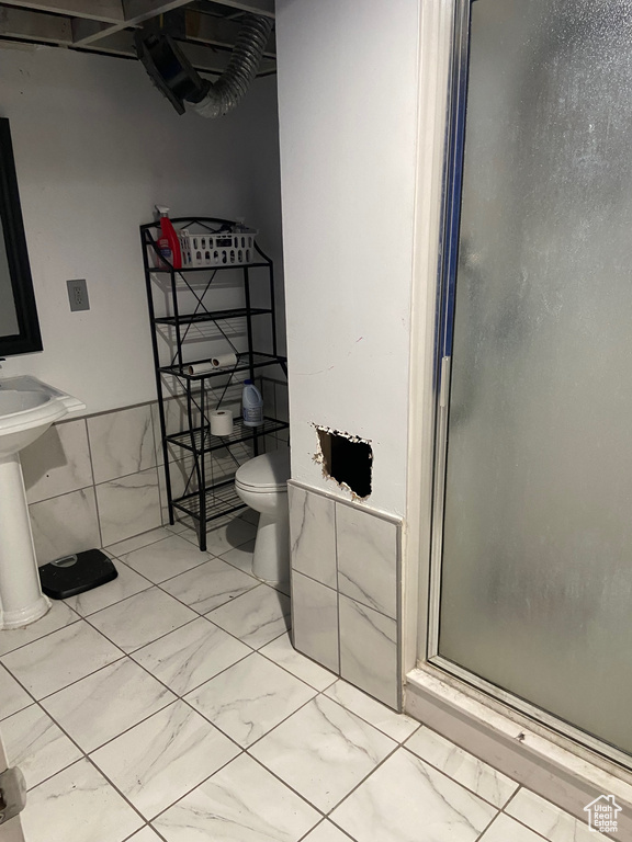 Full bathroom with marble finish flooring, a shower stall, and toilet