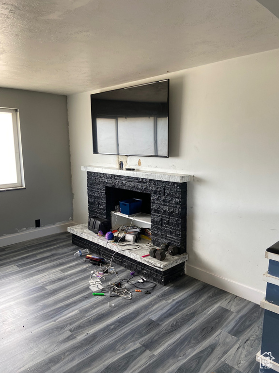 Detailed view of a fireplace, wood finished floors, baseboards, and a textured ceiling