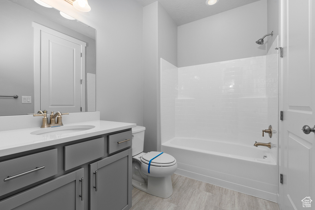 Full bathroom with vanity, wood finished floors, toilet, and shower / bath combination