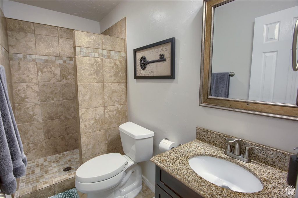 Bathroom featuring toilet, vanity, and tiled shower