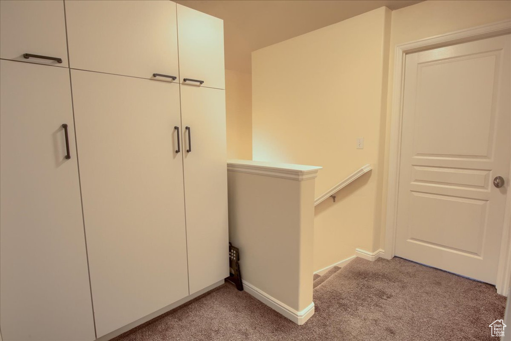 Hall featuring an upstairs landing, light carpet, and baseboards