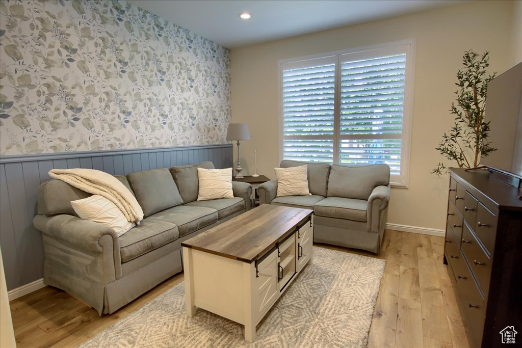 Living room with wallpapered walls, light wood-type flooring, recessed lighting, wainscoting, and baseboards