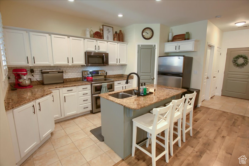 Kitchen with stainless steel appliances, a sink, tasteful backsplash, white cabinetry, and recessed lighting
