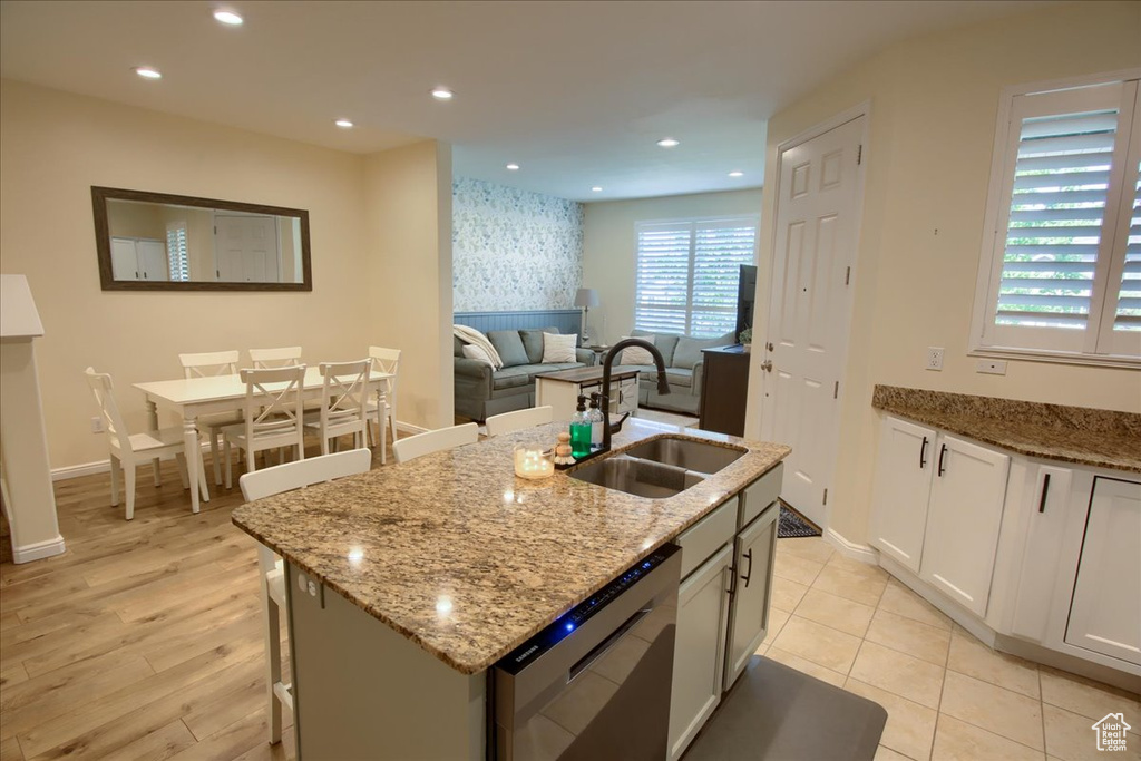 Kitchen featuring dishwasher, a sink, baseboards, light stone counters, and recessed lighting