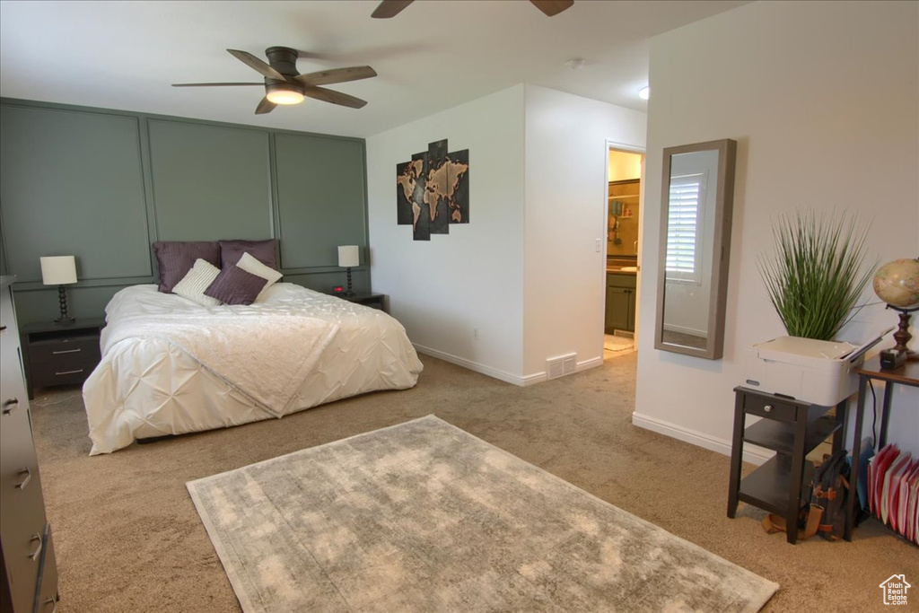 Carpeted bedroom with a ceiling fan, baseboards, and connected bathroom