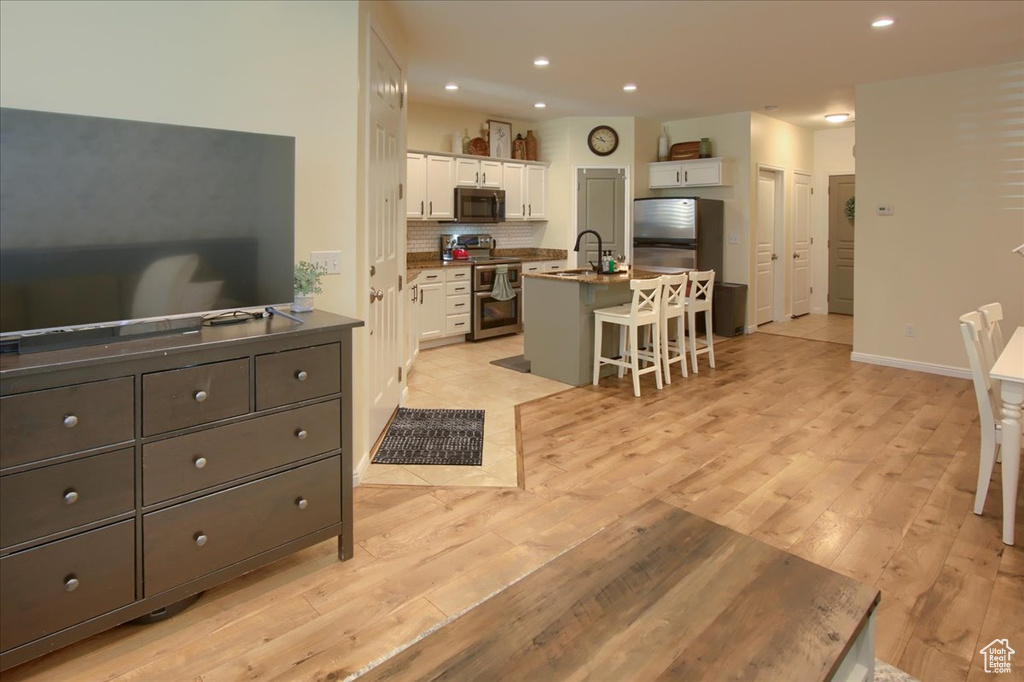 Living room with light wood-type flooring, recessed lighting, and baseboards