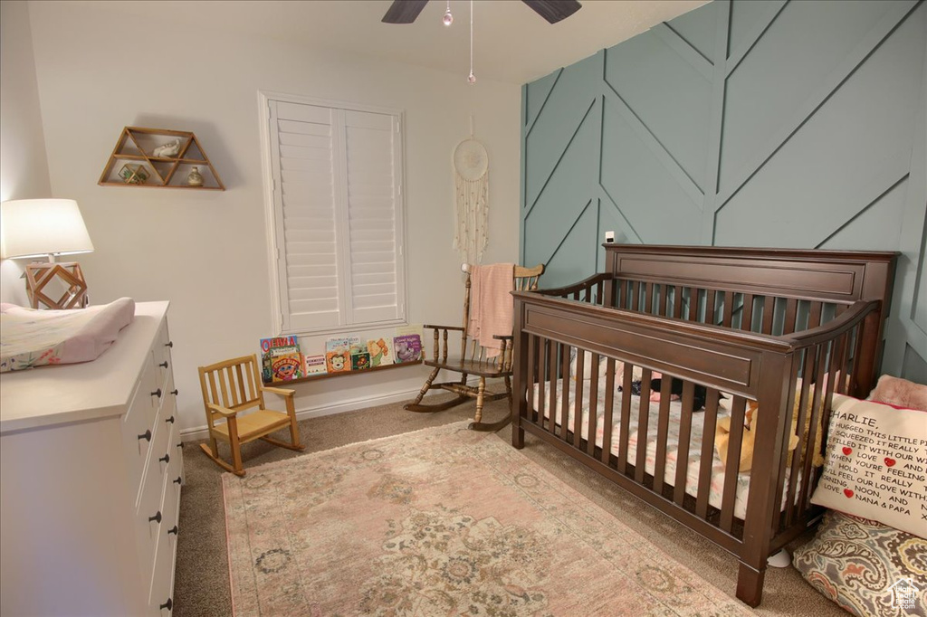 Bedroom with a crib, carpet flooring, ceiling fan, and baseboards