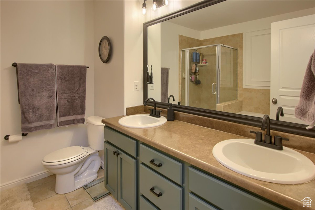 Full bathroom featuring a stall shower, toilet, double vanity, and tile patterned floors