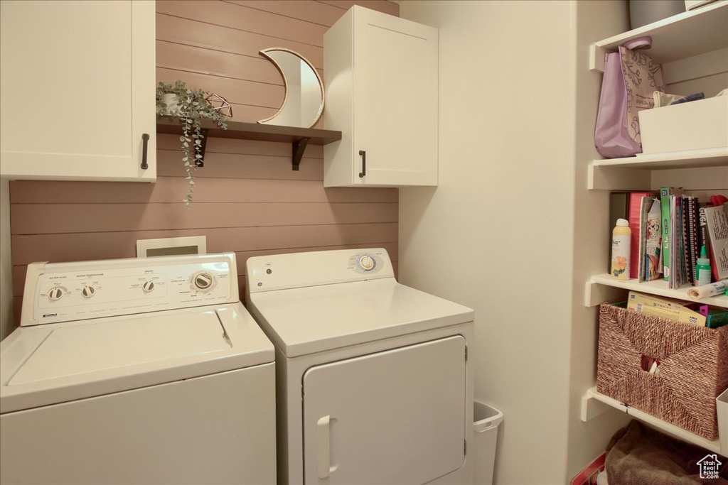 Washroom with washer and dryer, cabinet space, and wooden walls