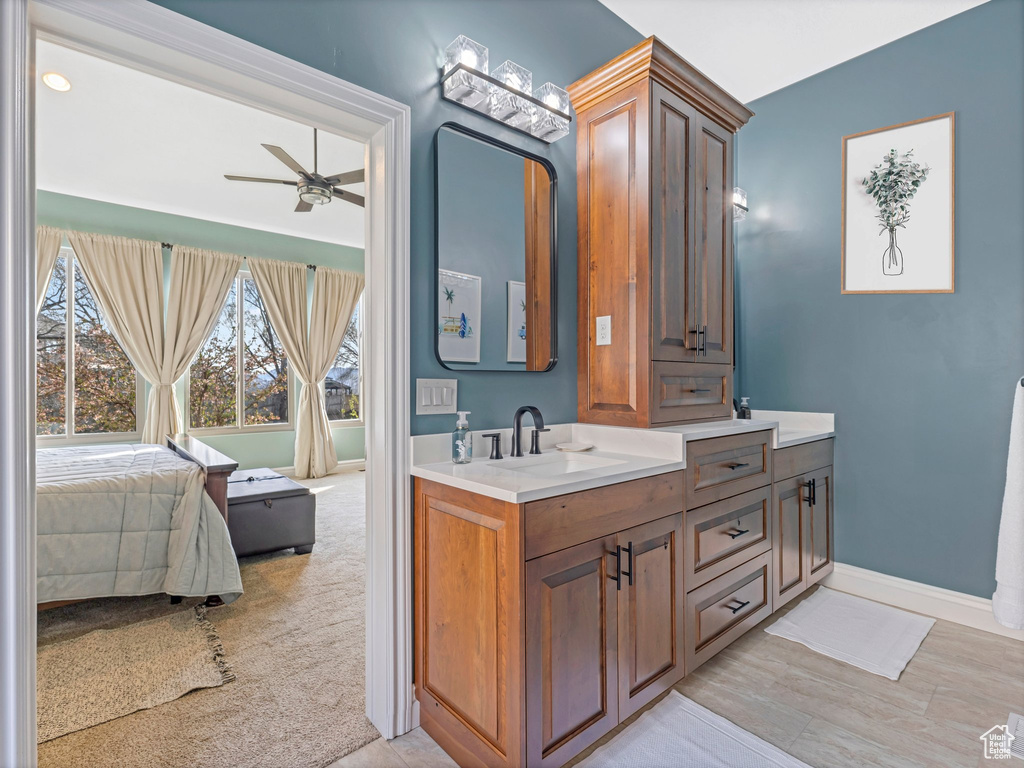 Ensuite bathroom with vanity, ceiling fan, and healthy amount of natural light