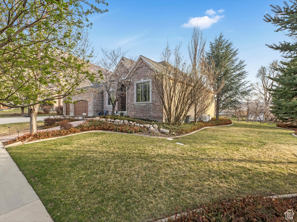 View of front of home featuring a front yard, a garage, driveway, and brick siding