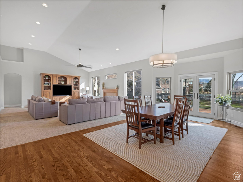 Dining area featuring arched walkways, ceiling fan, high vaulted ceiling, french doors, and wood finished floors