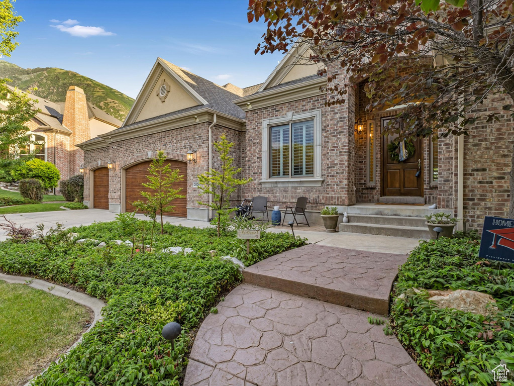 View of front of home featuring brick siding, driveway, a garage, and roof with shingles