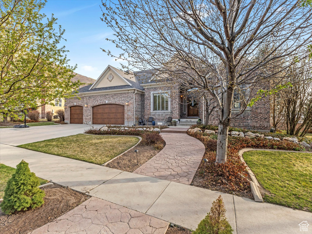 View of front of home featuring brick siding, concrete driveway, a front lawn, and a garage