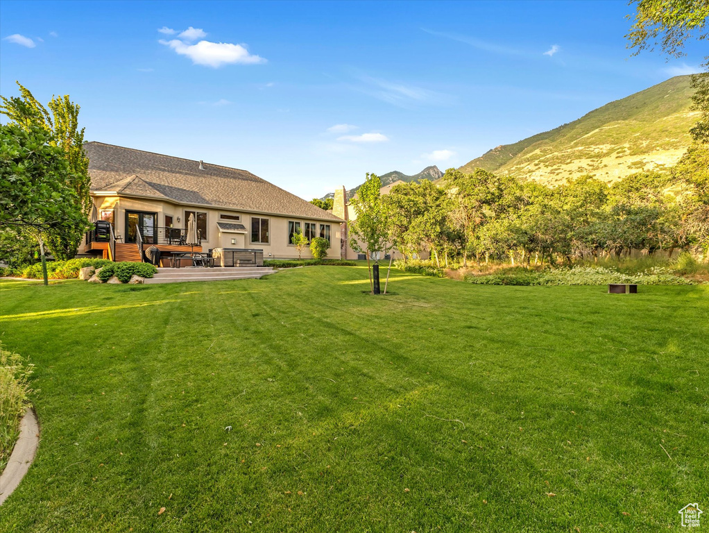 View of green lawn with a deck with mountain view