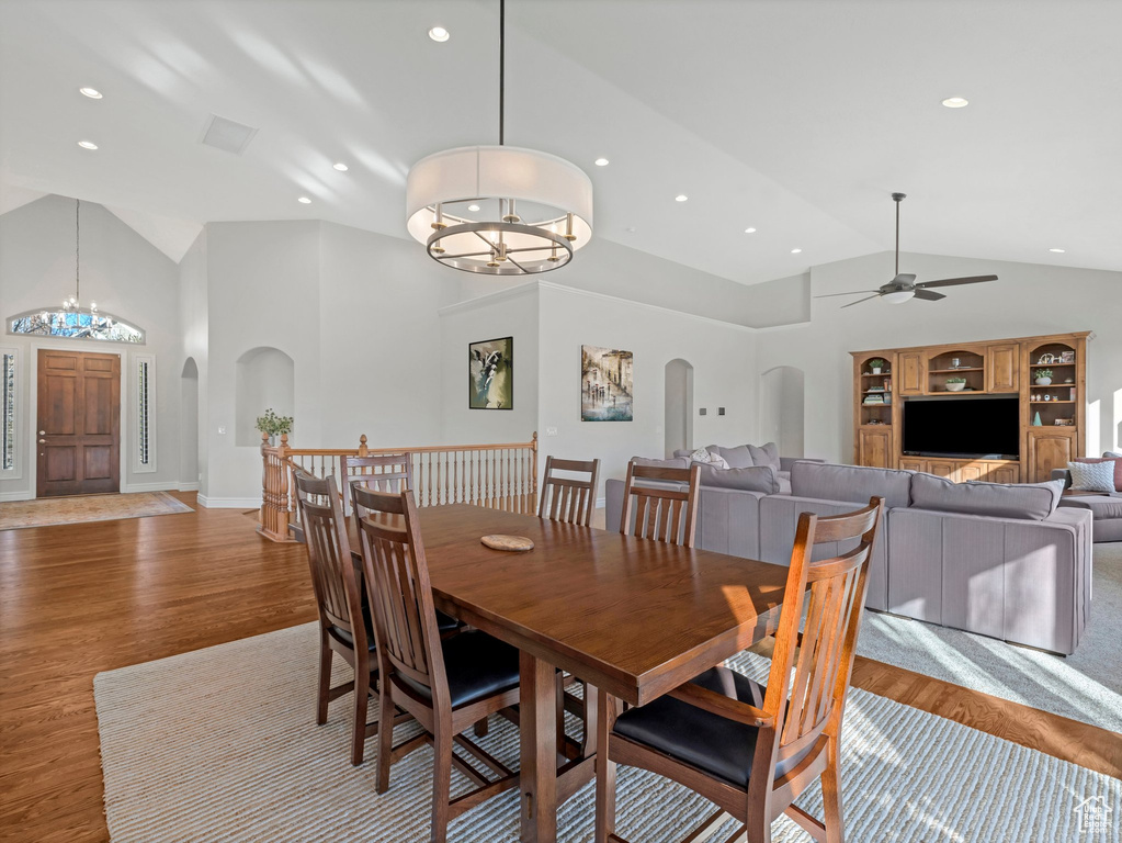 Dining room featuring arched walkways, a chandelier, light wood-type flooring, ceiling fan, and high vaulted ceiling