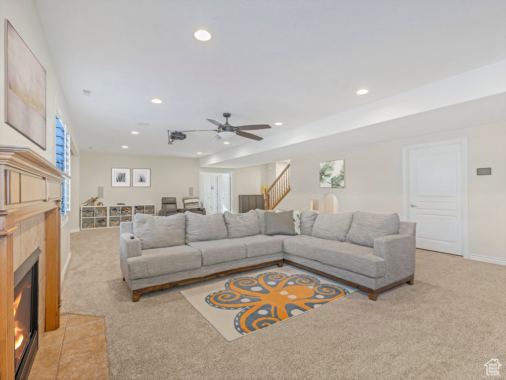 Living room featuring light carpet, recessed lighting, ceiling fan, a tile fireplace, and stairway