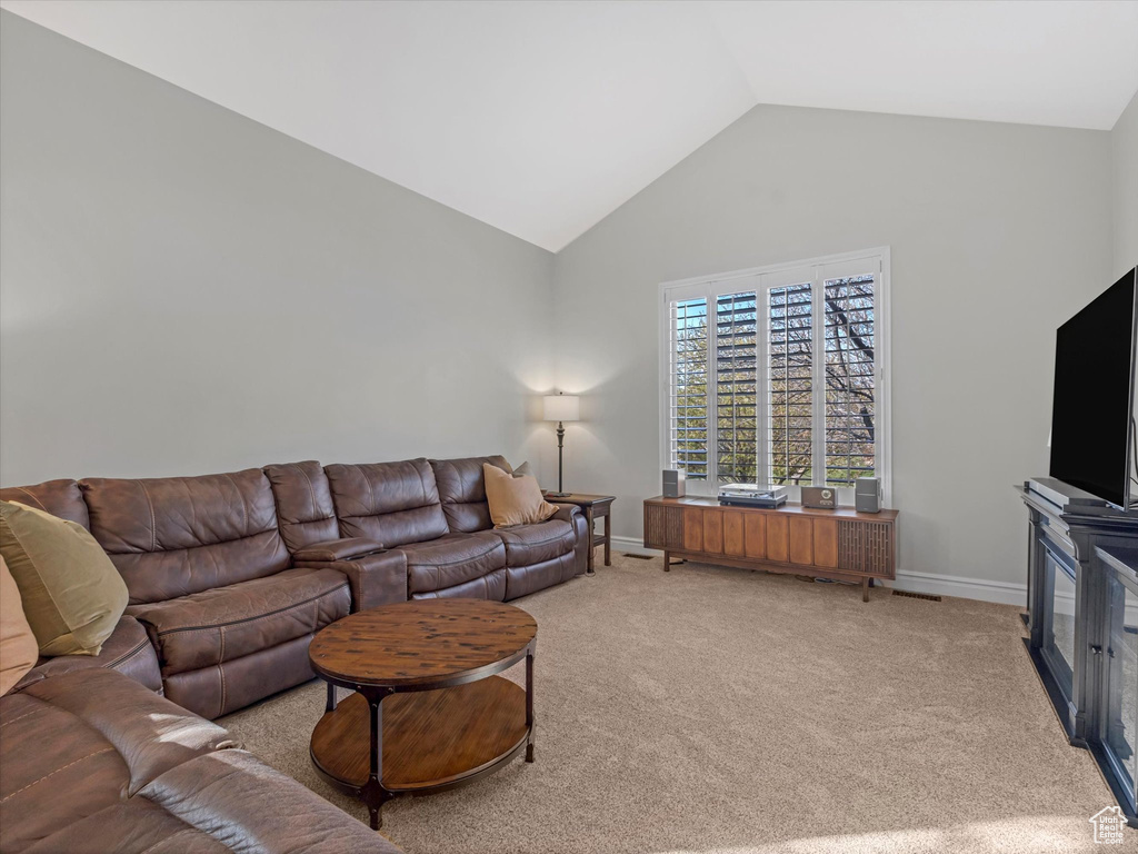 Living room featuring baseboards, carpet floors, and high vaulted ceiling
