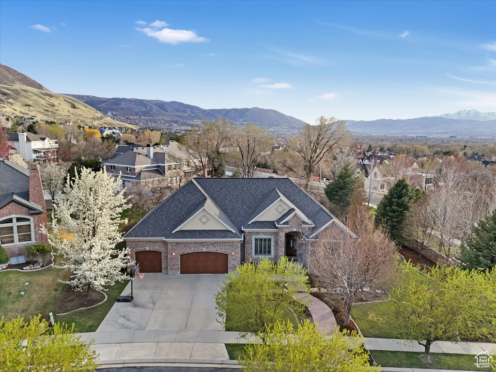 View of front of home featuring an attached garage, concrete driveway, a mountain view, brick siding, and a residential view