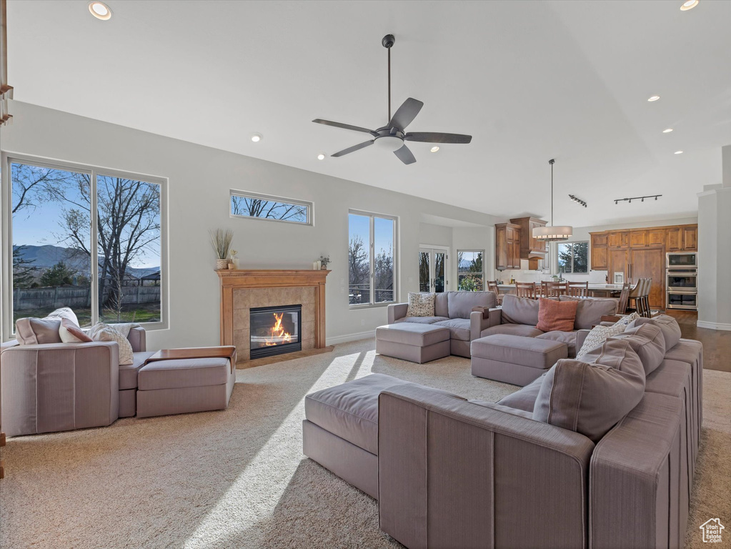 Living room featuring ceiling fan, a tiled fireplace, plenty of natural light, light carpet, and recessed lighting
