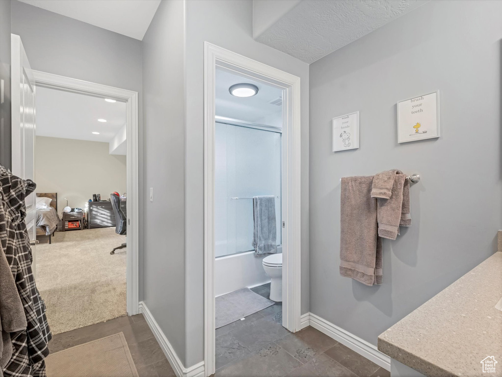 Bathroom with toilet, baseboards, washtub / shower combination, and vanity