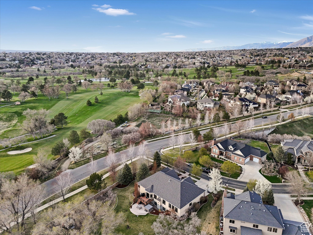 Aerial overview of property's location featuring nearby suburban area, a local golf course, and a mountainous background