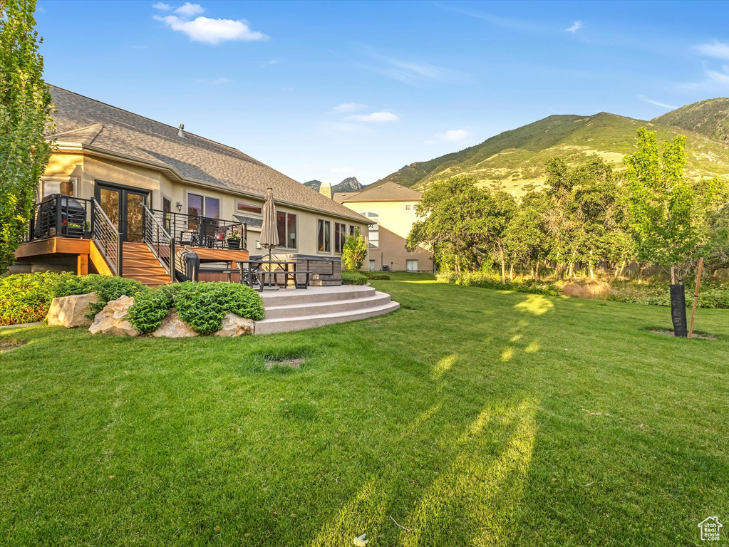 View of grassy yard featuring a deck with mountain view