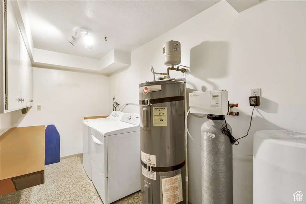 Laundry room with washer and dryer, water heater, cabinet space, and baseboards