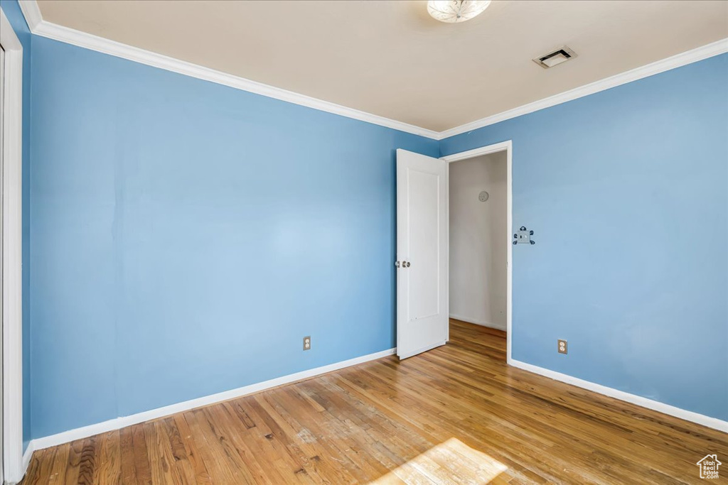 Unfurnished room featuring baseboards, wood finished floors, and crown molding
