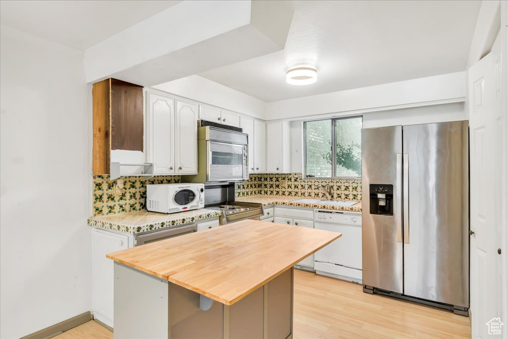 Kitchen featuring stainless steel appliances, butcher block counters, and tasteful backsplash