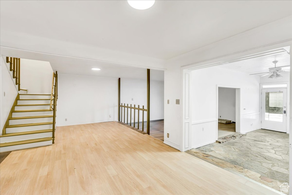 Unfurnished room with ceiling fan, stairway, and wood finished floors