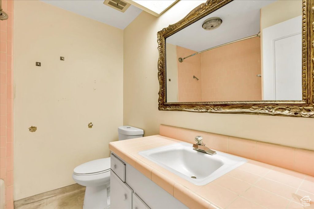 Full bath with toilet, vanity, and a shower
